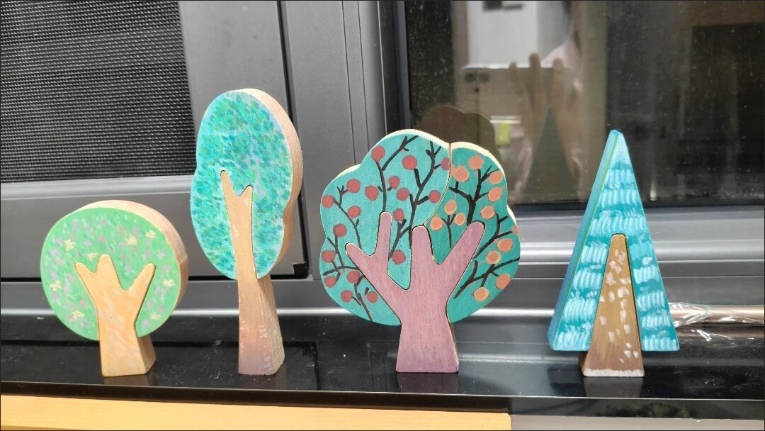 Real customer painted wooden trees displayed on a windowsill