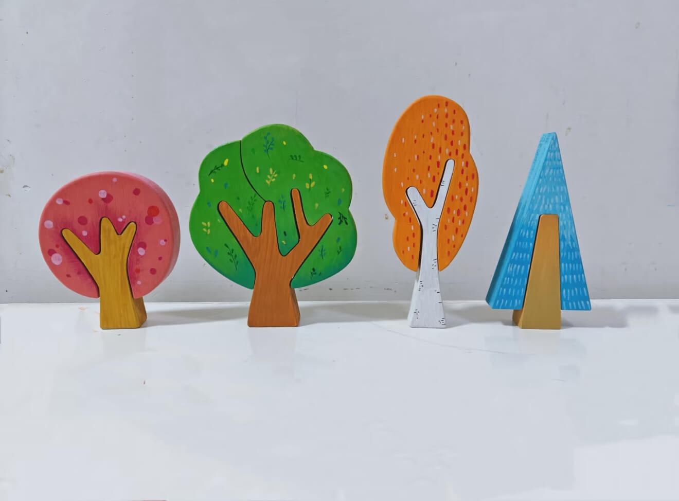Four colorful customer painted wooden trees on a light background