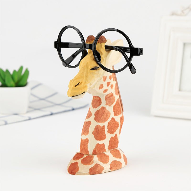 Wooden giraffe eyeglass stand holding spectacles on office desk