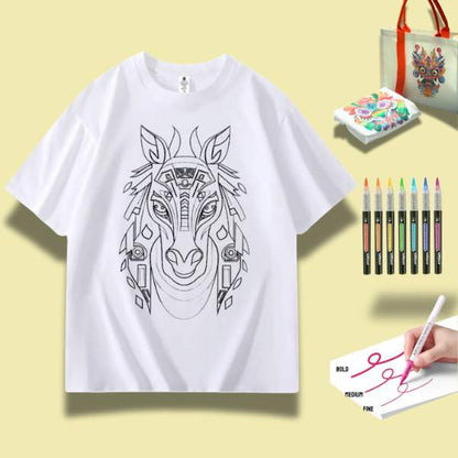 A white t-shirt featuring a detailed doodle of a proud house, surrounded by art supplies including markers and watercolor paints.