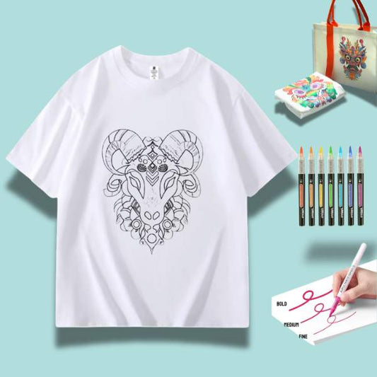A white t-shirt featuring a detailed doodle of a proud goat, surrounded by art supplies including markers and watercolor paints.