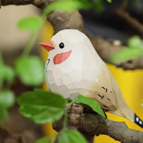 A small painted gray wooden Painted-Partridge perches gently on a twisted branch