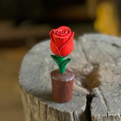Hand holding a carved wooden rose with natural wood petals