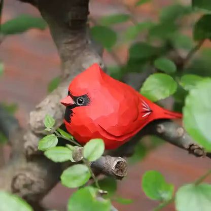 A detailed red cardinal bird resting on a branch surrounded by green leaves.