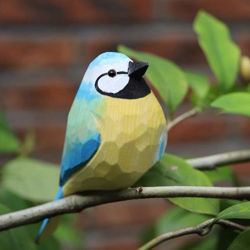 A chubby wooden bird sculpture painted in vibrant blue and yellow with a black beak, decorated using acrylic paint for a bold and cheerful look.