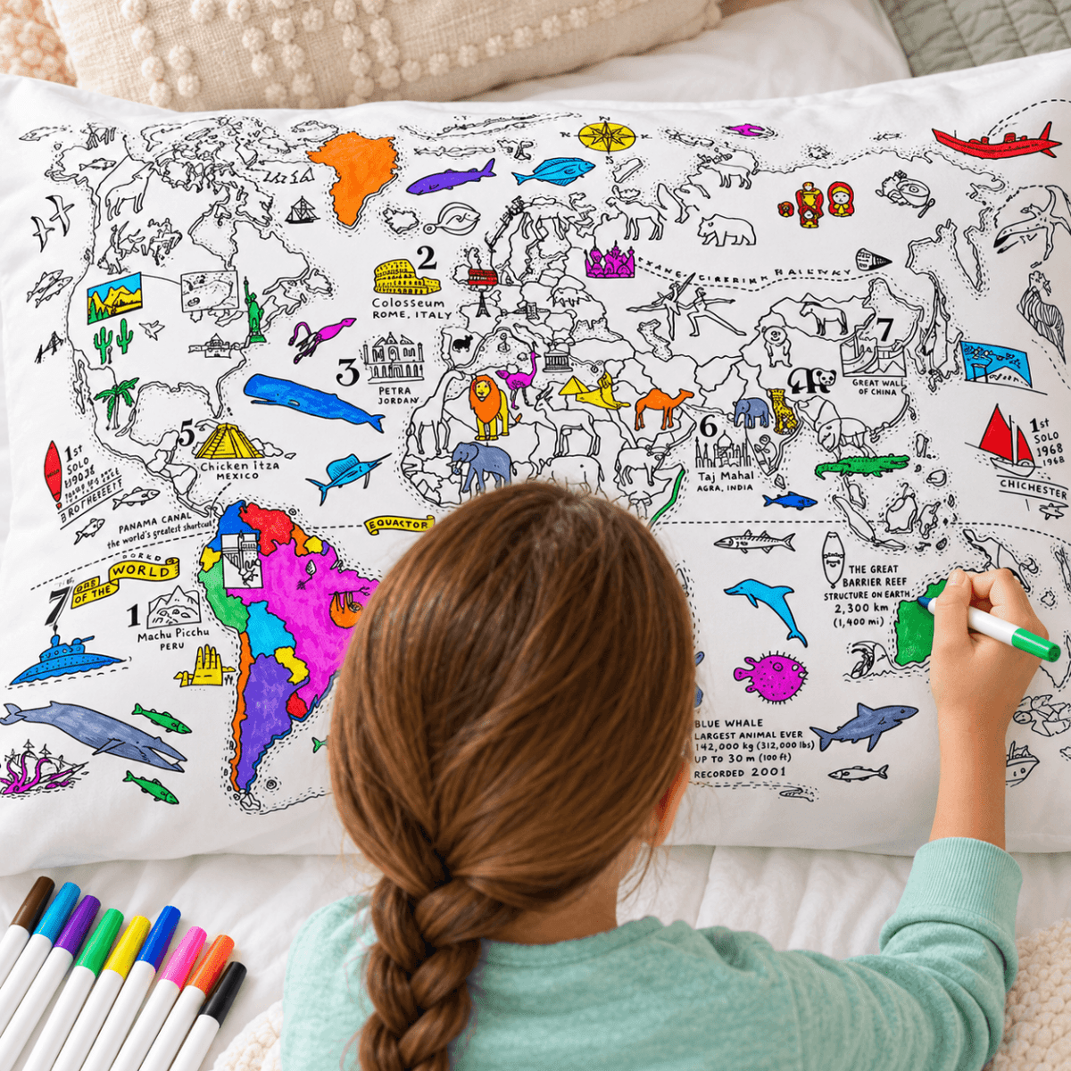 Back view of a child coloring a detailed world map pillowcase with fabric markers