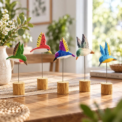 Five colorful wooden hummingbird ornaments on wood-base stands in a bright home display