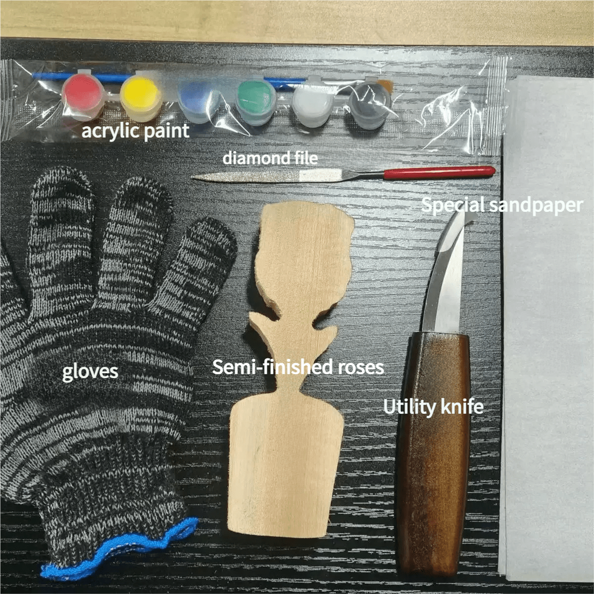 An assortment of crafting tools including acrylic paint, a diamond file, gloves, semi-finished wooden roses, a utility knife, and special sandpaper.