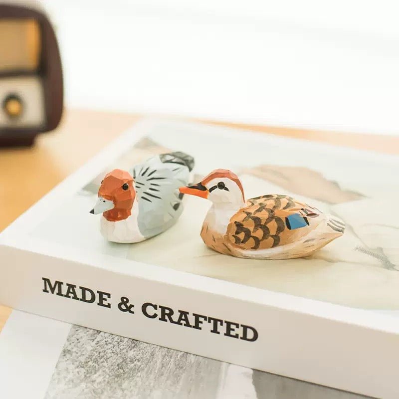 Two handcrafted duck figurines placed on a white surface.