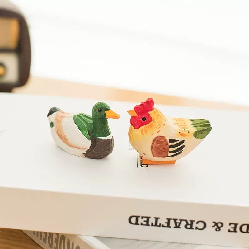 Two carved wooden dog figures sitting on a newspaper with a decorative tree in the background.