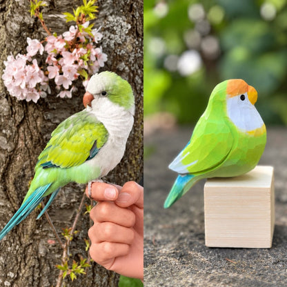 Hand holding colorful painted wooden parrot figurines outdoors near flowers