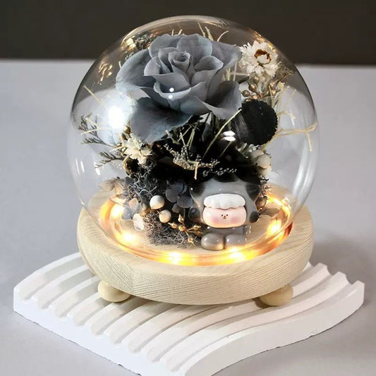 A beautifully crafted glass dome featuring a grey rose and decorative elements, creating an elegant product display.