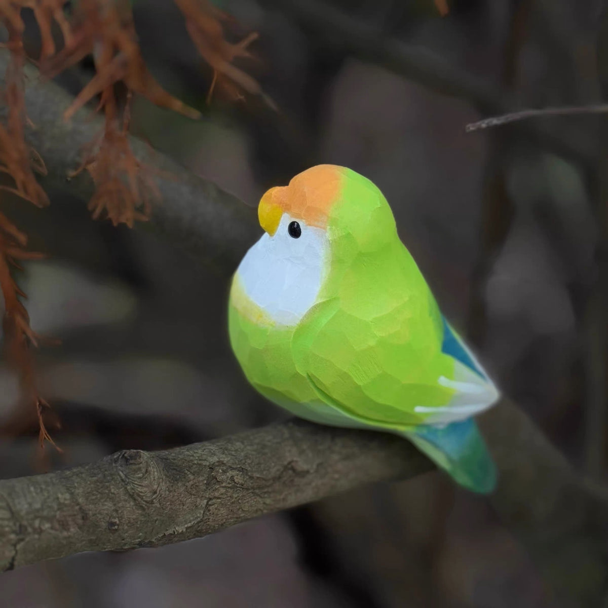 Green hand-painted wooden parrot sitting on a tree branch