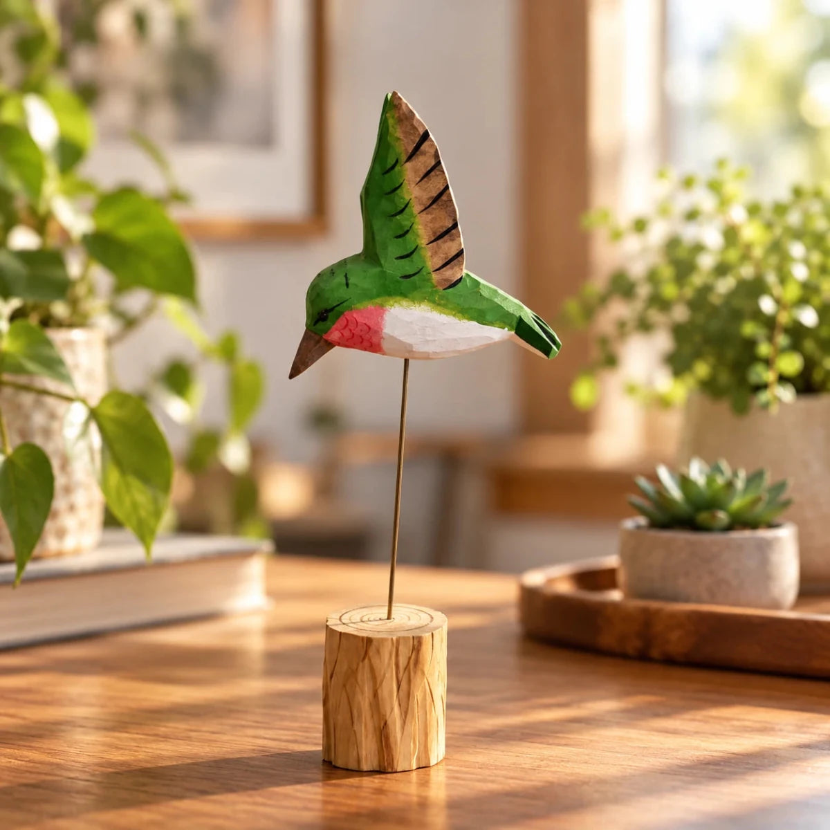 Green hand-painted wooden hummingbird ornament on a wire stand on a sunlit table