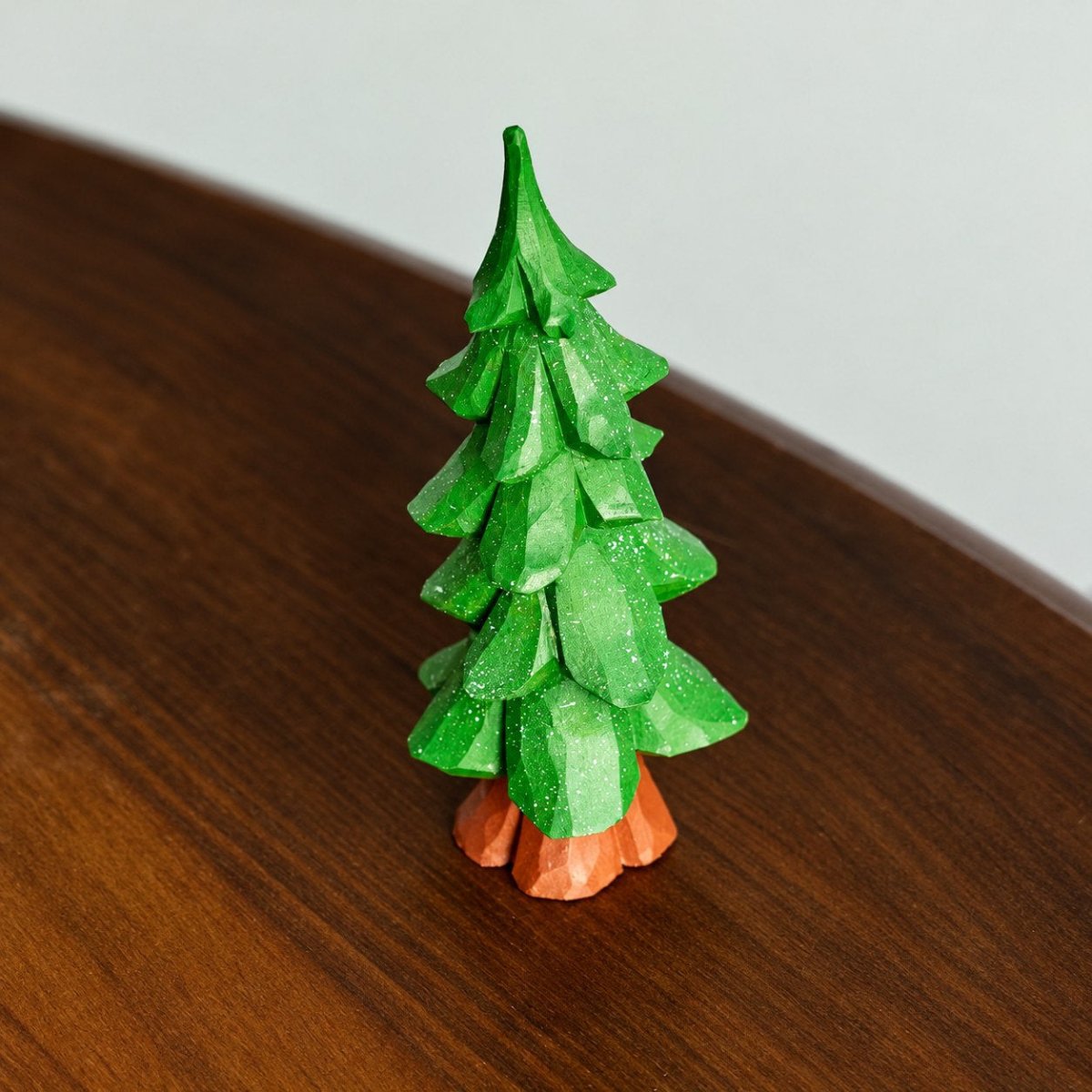 Tall green hand-painted wooden Christmas tree figurine on a tabletop
