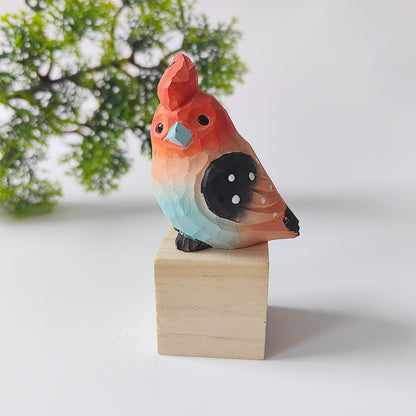 Coral and black hand-carved wooden budgie figurine on a walnut base