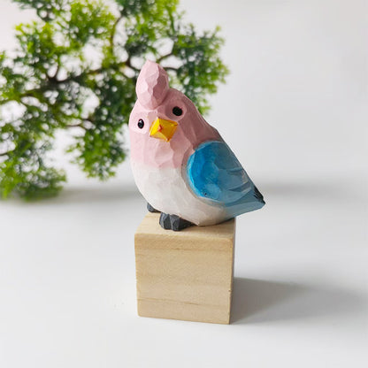 Pink and blue hand-carved wooden budgie figurine on a walnut base