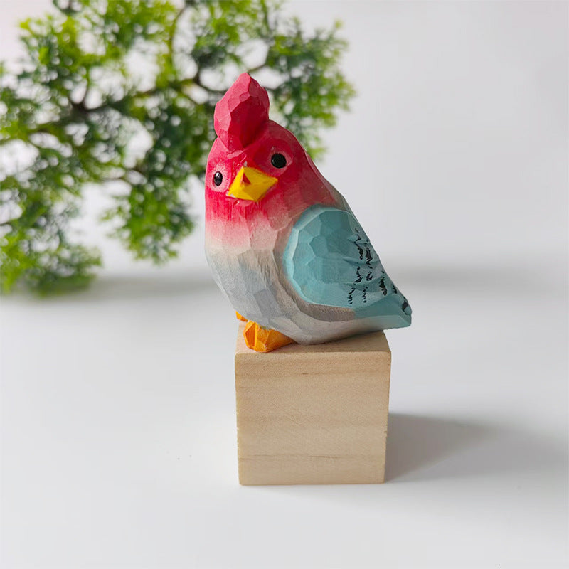 Red and blue hand-carved wooden budgie figurine on a walnut base