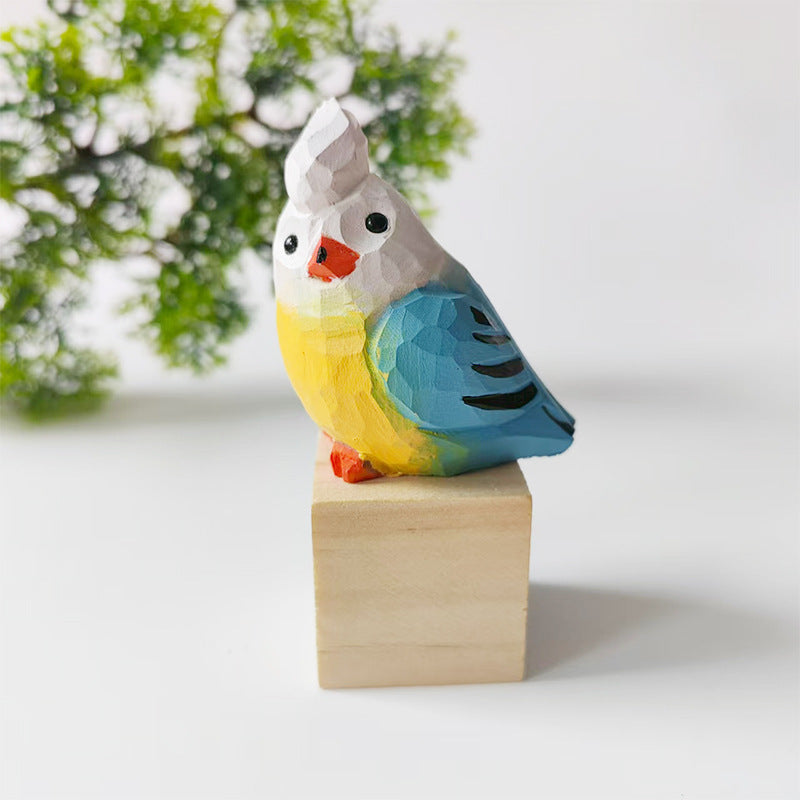 White and blue hand-carved wooden budgie figurine on a walnut base