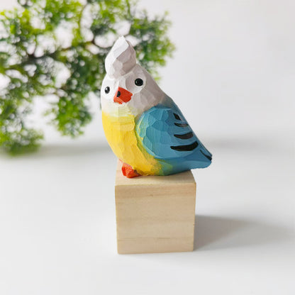 White and blue hand-carved wooden budgie figurine on a walnut base
