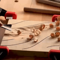 Hands using a professional gouge chisel to carve detailed patterns into a wood block