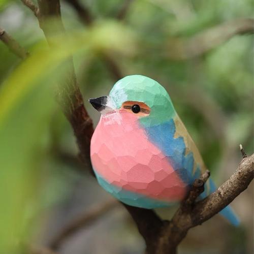 Close-up of a carved basswood bird with vibrant purple and blue wings on a branch 🪶🪵