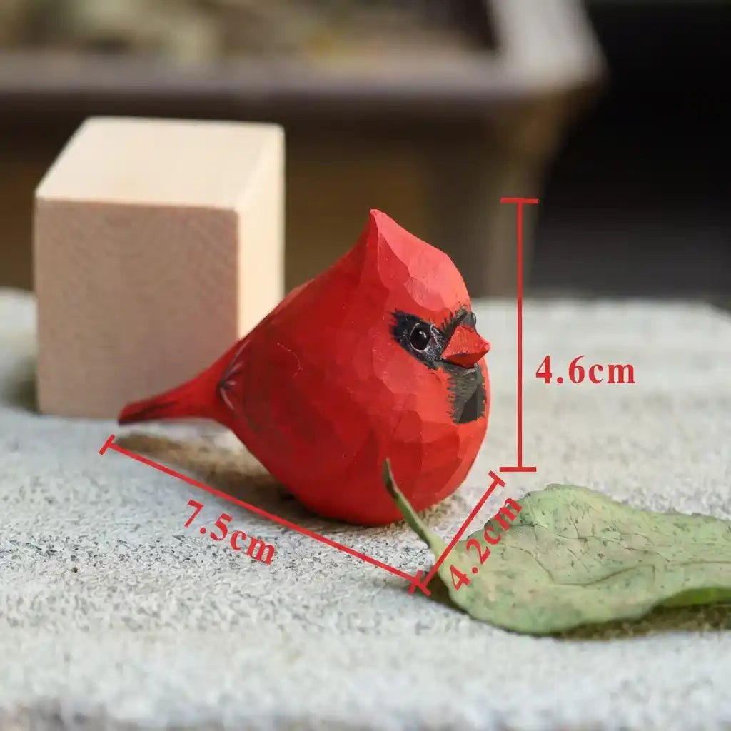 A detailed red cardinal figurine on a stone surface with measurements shown