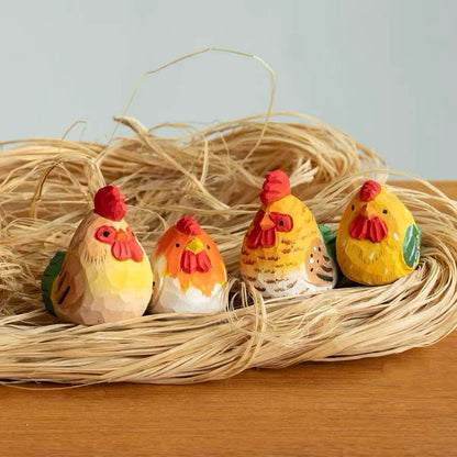Hand-painted wooden rooster and hen figurines displayed together in a woven nest