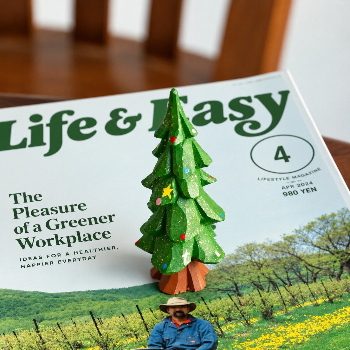 Hand-painted wooden Christmas tree displayed on an open magazine in a cozy home setting