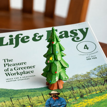 Hand-painted wooden Christmas tree displayed on an open magazine in a cozy home setting