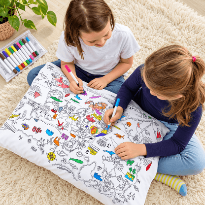 Two girls coloring a detailed world map pillowcase together with fabric markers