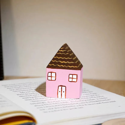 Pink painted wooden house displayed on an open English book