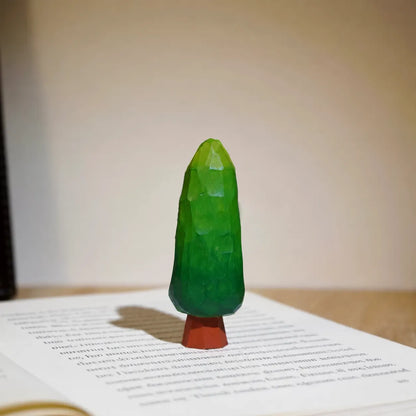 Small green painted wooden tree displayed on an open English book