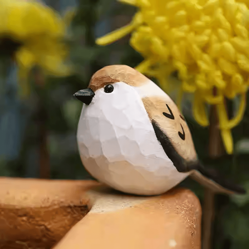 Artisan carved painted sparrow bird perched naturally on a tree branch outdoors