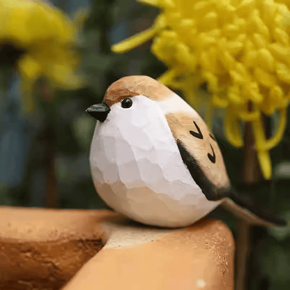 Artisan carved painted sparrow bird perched naturally on a tree branch outdoors