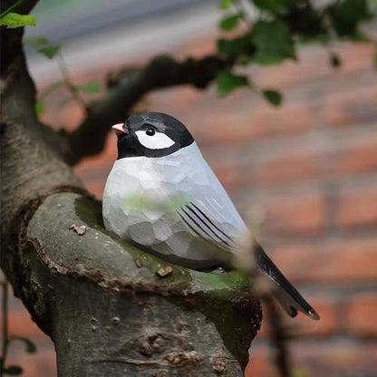A gray wooden painted swallow perches on a tree branch
