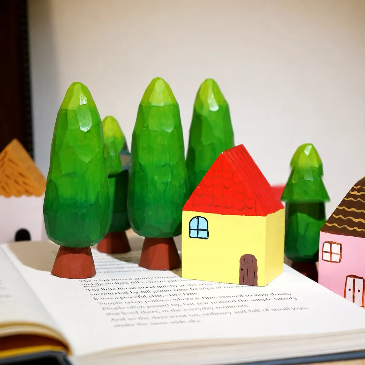 Painted wooden houses and trees arranged together on an open book