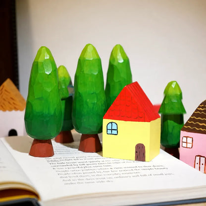 Painted wooden houses and trees arranged together on an open book