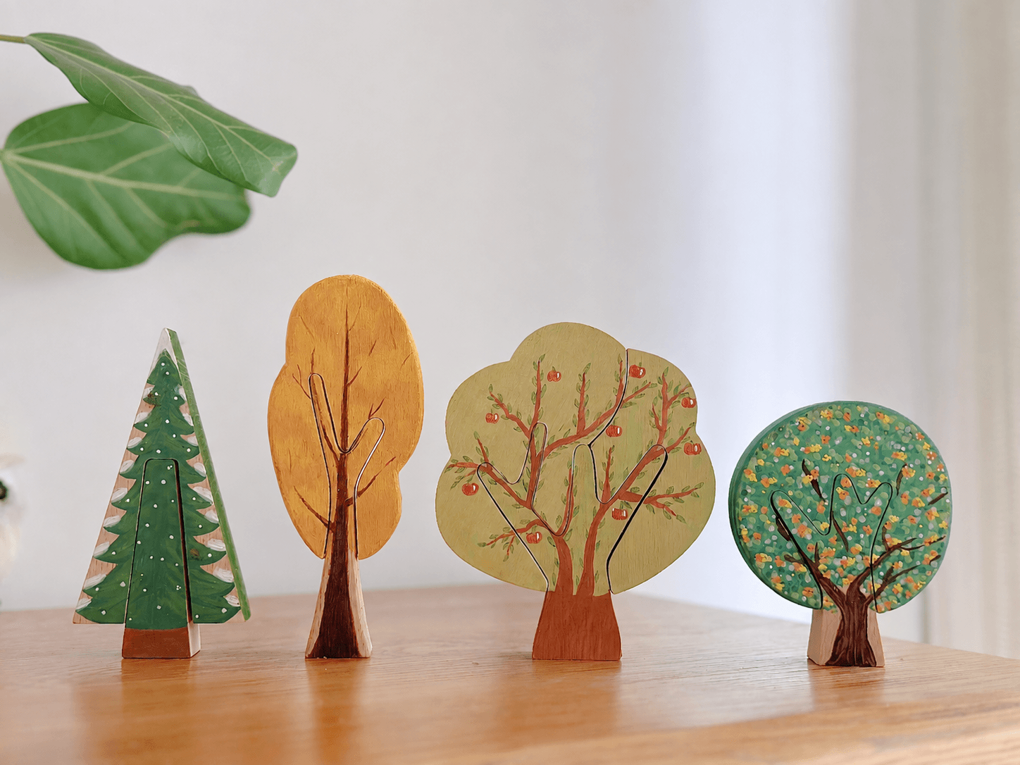 Four painted wooden tree shapes styled indoors