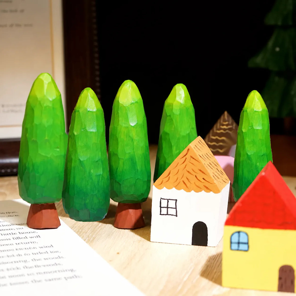 Painted wooden trees and houses arranged in a colorful tabletop village scene