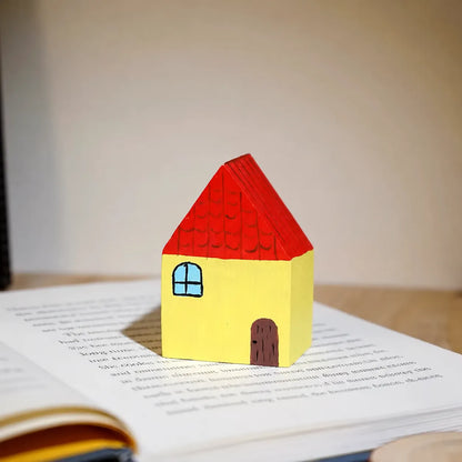 Yellow and red painted wooden house displayed on an open English book