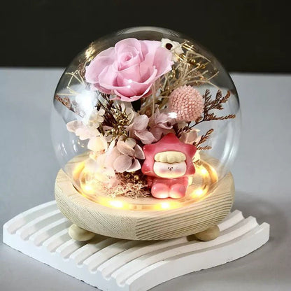 DIY preserved flower arrangement in a glass dome featuring pink hydrangeas and a kid