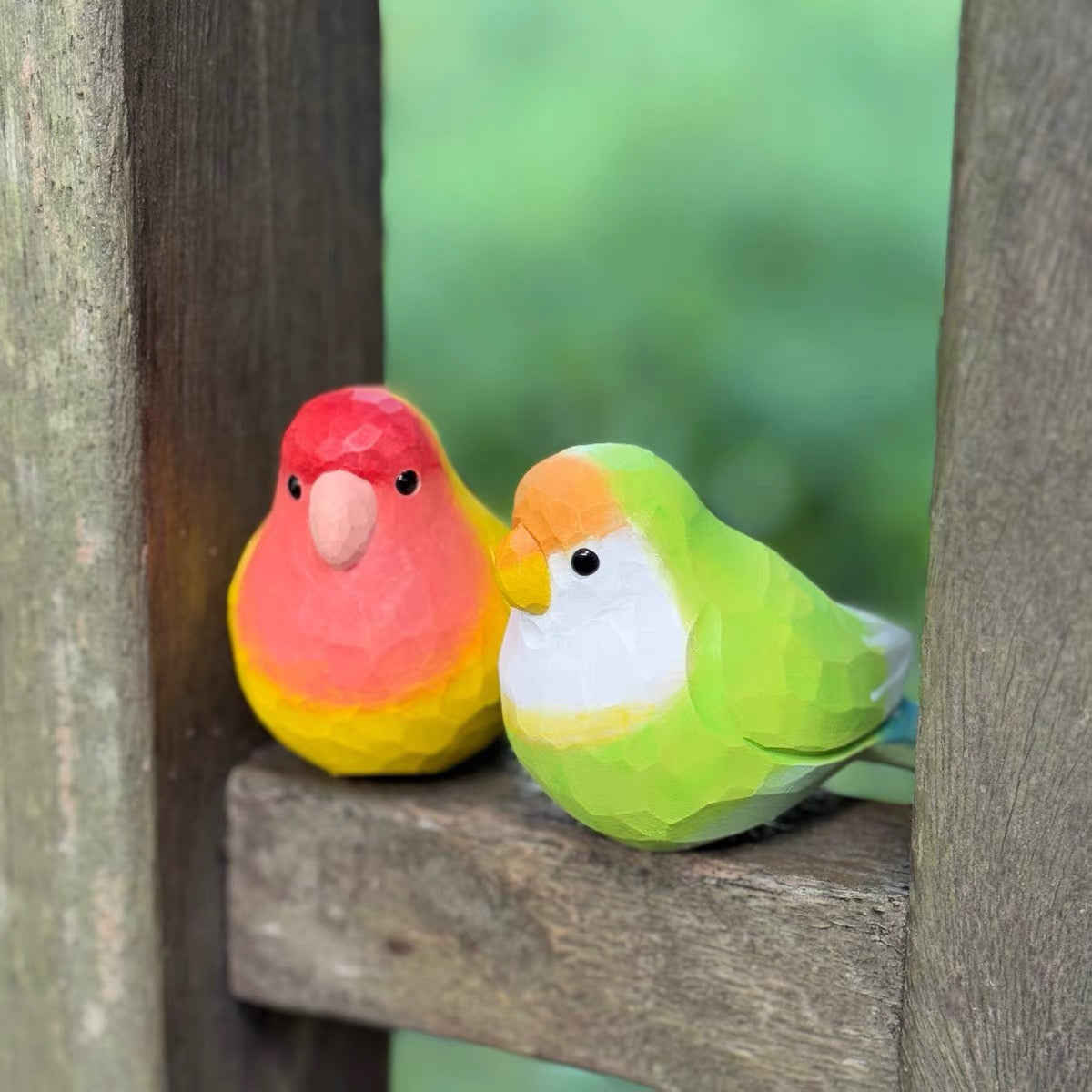 Red yellow and green hand-painted wooden parrot pair outdoors