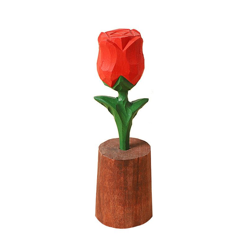A beautifully carved wooden rose with vibrant red petals and green leaves, resting on a wooden base.