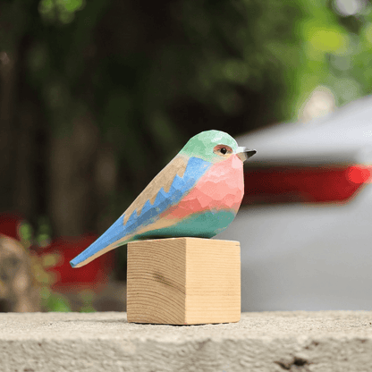 A beautifully crafted wooden bird figurine painted in vibrant colors, resting on a wooden block.