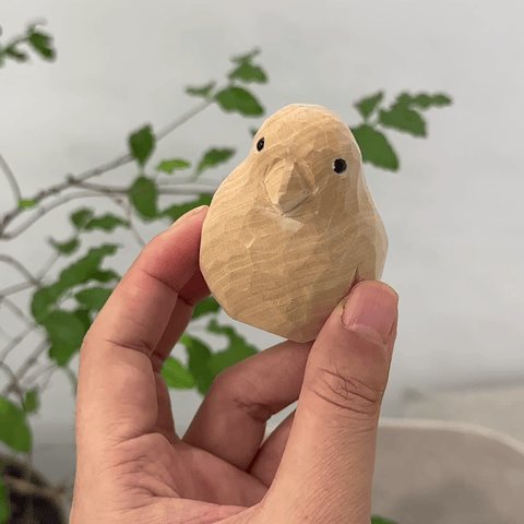 Hand holding an unfinished wooden parrot figurine ready for painting