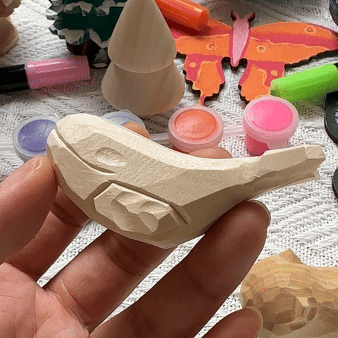 A hand holding a carved wooden whale figure with colorful paints in the background.