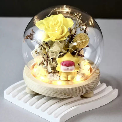 DIY preserved flower arrangement in a glass dome featuring yellow hydrangeas and a kid